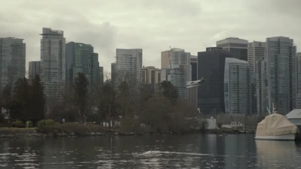 Wide Panning Shot Sea Plane Landing Trees Downtown Vancouver Cloudy — стоковое видео