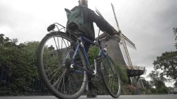 Yel Değirmeninin Yanında Bisikletle Yürüyen Genç Hollandalı Kadın — Stok video
