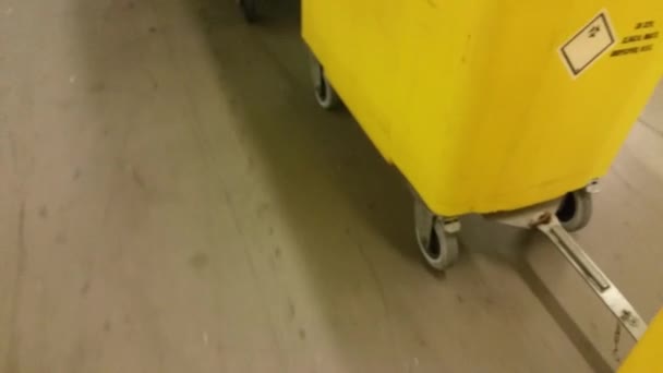 Yellow Waste Containers Rolling Lit Corridor — Video