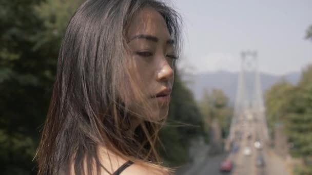 Closeup Asian Woman Black Looking Forward Lions Gate Bridge Background — Stock video