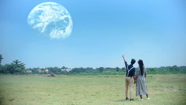 一对浪漫的夫妻 男孩和女孩站在草原上 在梦中或科幻小说中看着新的星球地球 — 图库视频影像