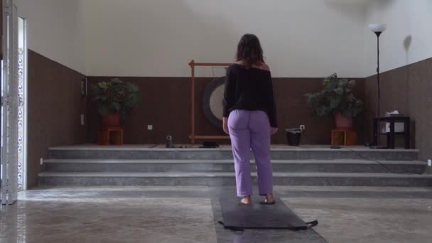 女の子は大きなゴングで瞑想ホールでヨガをします — ストック動画