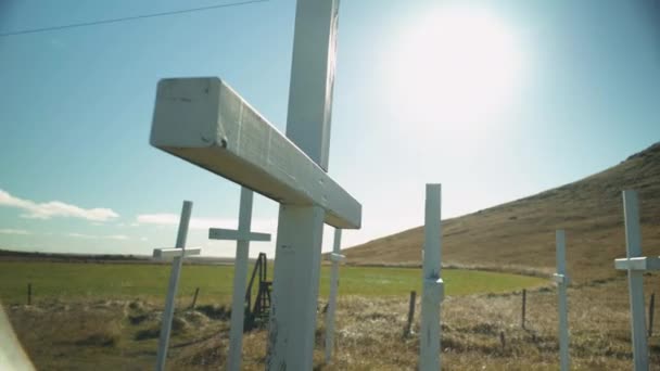 アイスランドの小さな山の近くに白い十字架の列の後ろに太陽が沈む — ストック動画