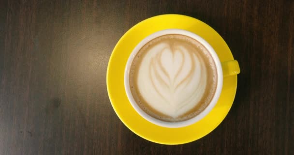放在桌上的黄色杯子和茶托上的咖啡拿铁的俯视图 — 图库视频影像