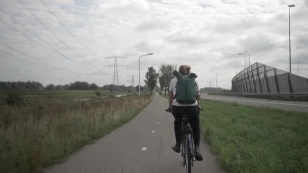 自転車に乗る女性 女性の自転車とサイクリング晴れた日のヨーロッパで バックパックからの眺め 自動車道の隣の自転車道の屋外 — ストック動画