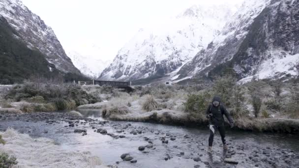 Повільний Рух Дівчини Пішохідному Спорядженні Перетинає Річку Оточенні Снігових Гір — стокове відео
