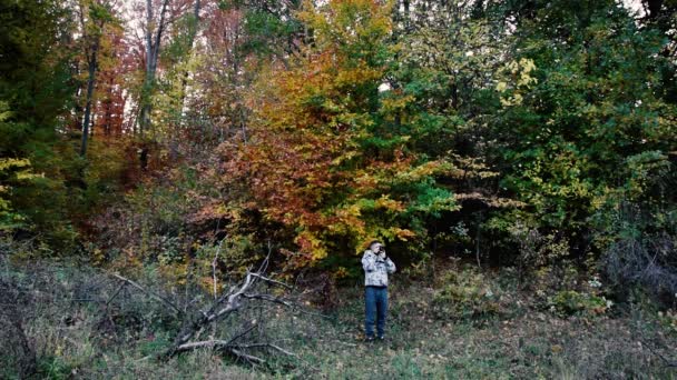 Человек Толстовке Смотрит Вперед Фотографирует Природе Осенний Сезон Возле Леса — стоковое видео