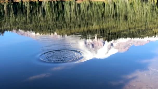 美国华盛顿州的雷尼尔山映照在湖面上 石头被抛入水中 产生波纹 搅乱平静的水面 慢动作拍摄 — 图库视频影像