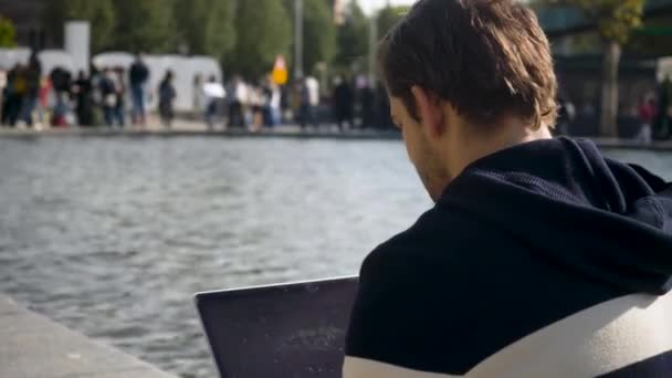 Bonito Jovem Sentado Margem Canal Amsterdã Digitando Laptop Países Baixos — Vídeo de Stock