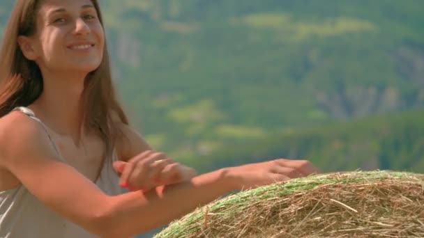 フランスの農場で干し草の大規模なベールにもたれながら 美しいブルネットの女性の笑顔と笑いのクローズアップ — ストック動画