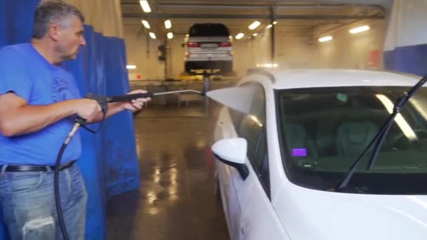 Arbeiter Versprühen Wasser Und Waschen Die Scheiben Eines Weißen Geländewagens — Stockvideo