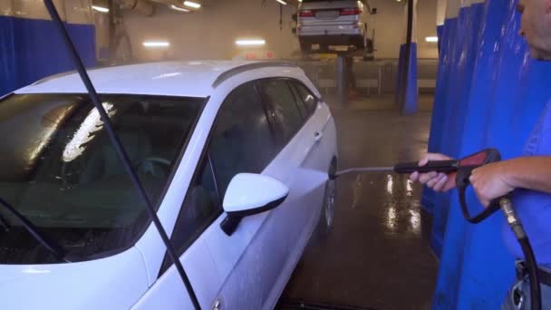瑞典卡沃什的工人喷洒水和清洗一辆白色越野车 — 图库视频影像