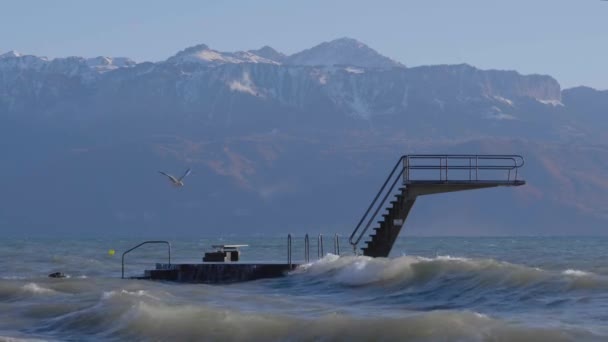 Diving Board Windy Day Waves Crashing Structure Alps Covered Snow — Stock videók