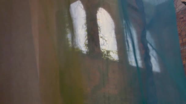 興味深い石のアーチの上にギリシャのアパートの色のカーテンを通して見て遅い動きの焦点を引くショット — ストック動画