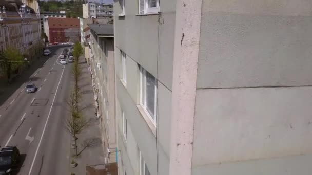 都市の建物の側面の空中ドローンショット予期せず屋上の端に立つ若い大人の男性の足を明らかに — ストック動画