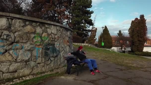 Mladý Dospělý Muž Sedí Lavičce Parku Neočekávaně Začíná Dělat Salta — Stock video