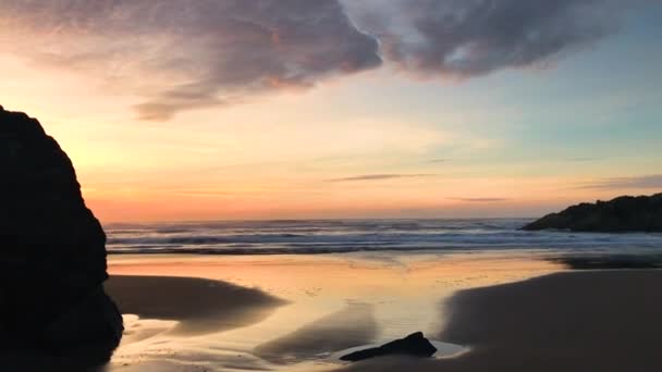 班顿海滩岩石上两个女孩的轮廓 其中一个在拍摄落日的照片 — 图库视频影像