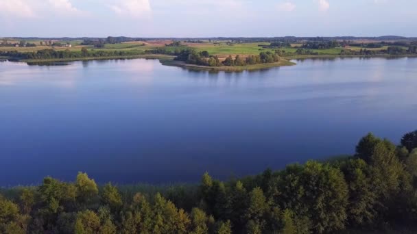 空中拍摄了一个偏僻的湖 周围是田野和农场 放松的风景 漂亮的颜色 沿着海岸横向飞行 下午很晚的时候波兰 — 图库视频影像
