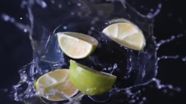 緑のライムフルーツの新鮮なスライスは スローモーションでスプラッシュと作品の中で水に落ちる — ストック動画