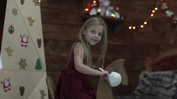 Mała Dobrze Ubrana Dziewczyna Gra Jeździ Drewnianym Koniem Dekoracje Świąteczne — Wideo stockowe