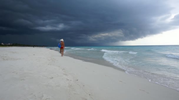 女性は美しい熱帯の砂浜を歩き 背景には熱帯性の嵐の到来のために空はすべて黒です スローモーション — ストック動画