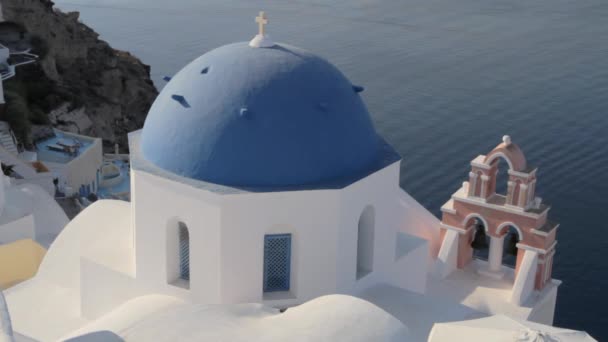 有名な青の教会のドーム ピンクの教会の鐘があるOia Santorini — ストック動画