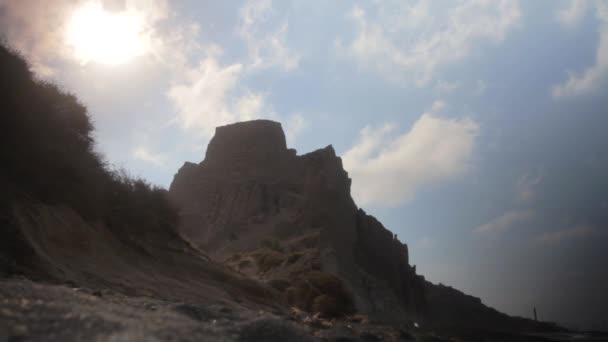 从地面 沙层看到的白色火山岩层 太阳在悬崖峭壁上闪耀 一件白衬衫在风中飘扬以遮挡太阳光 — 图库视频影像