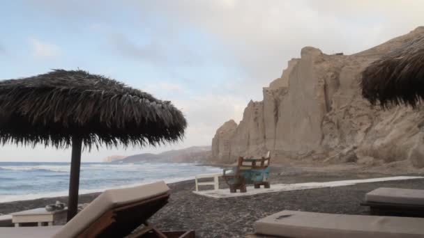 Halmstrand Paraply Och Strandsängar Den Svarta Stranden Santorini Med Vita — Stockvideo