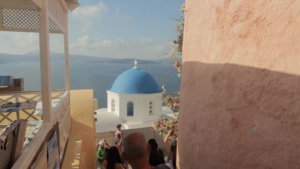 観光客はOia Santoriniのカルデラビューで有名な青いドーム礼拝堂の写真を撮って歩く — ストック動画