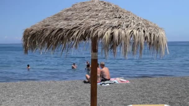黒い砂浜に1本のわらのビーチの傘 カマリビーチ サントリーニ島 — ストック動画