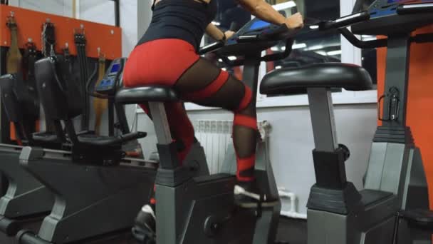在体育馆里的机器上骑着有氧自行车的女人的近视 — 图库视频影像