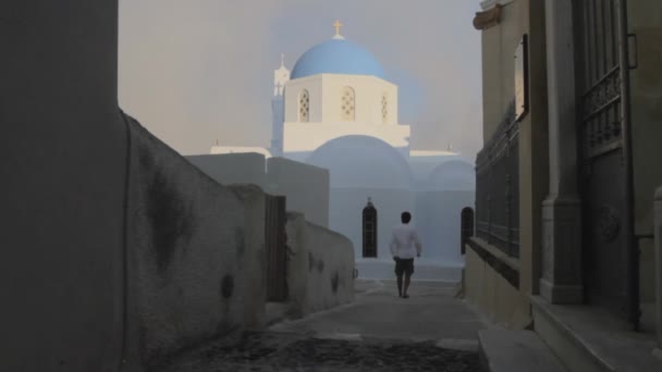 Mężczyzna Idzie Kierunku Greckiego Prawosławnego Cykladycznego Kościoła Niebieską Kopułą Potem — Wideo stockowe