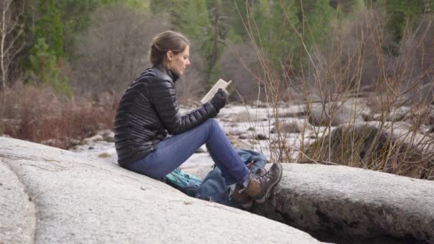 Mooie Vrouw Lezen Rots Buurt Van Een Rivier Een Wandeling — Stockvideo