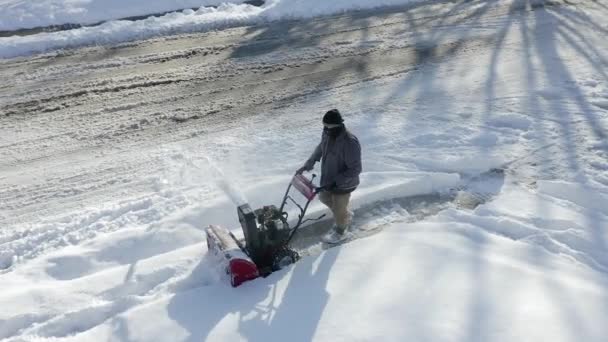 Aerial View Shows Man Snow Blowing Sidewalk — Stok video