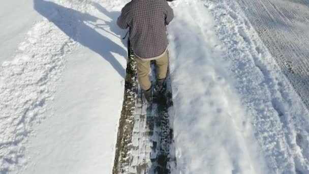 Aerial View Follows Man Sidewalk Using Snow Blower — Stok video