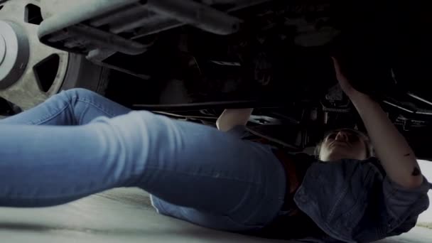 초반의 여성은 트럭의 아래를 확인하고 기계적 문제를 해결하기 아래로 갑니다 — 비디오
