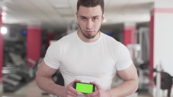 Ein Fitnesstrainer Steht Und Hält Sein Handy Der Hand Hat — Stockvideo