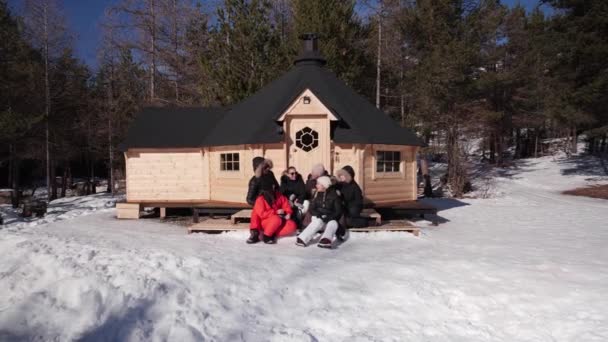 Happy Family Winter Vacation Sitting Snow Warm Cabin Woods — Stock video