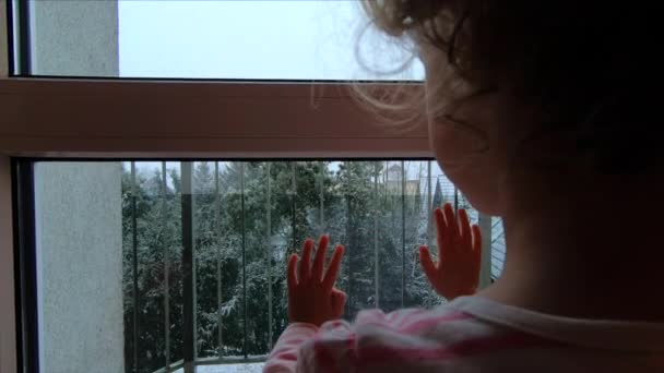 Ένα Κοριτσάκι Παρακολουθεί Από Παράθυρο Χιόνι Που Πέφτει — Αρχείο Βίντεο