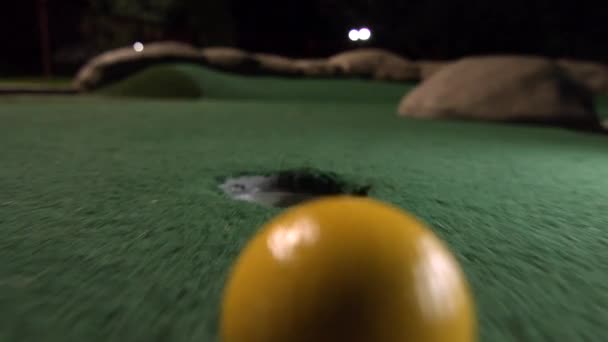 一只黄色的迷你高尔夫球掉进了高尔夫球洞里 弹出在一个弹夹漏掉的球道上的口袋里 — 图库视频影像