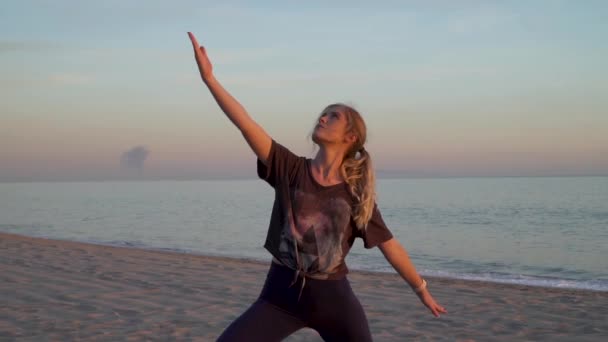 Yoga Instructor Doing Warrior Pose Beach Sunset Waves Flowing Background — стокове відео