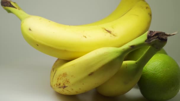 Yellow Ripe Bananas Lime Rotating Table White Background Close Shot — ストック動画