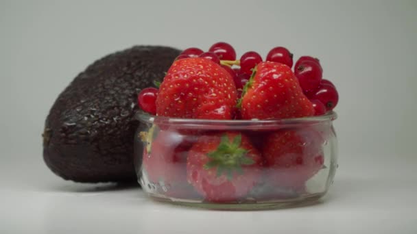 Ripe Avocado Strawberries Red Currants Clear Glass Bowl Rotating Close — ストック動画