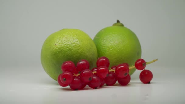 Two Green Sour Limes Red Currants White Turntable Close Shot — стокове відео