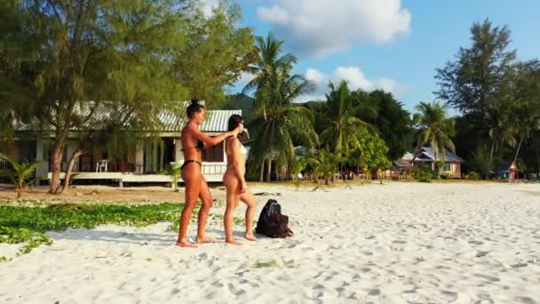 Two Beautiful Women Massaging Bodies Quiet Exotic Beach White Sand — Stockvideo