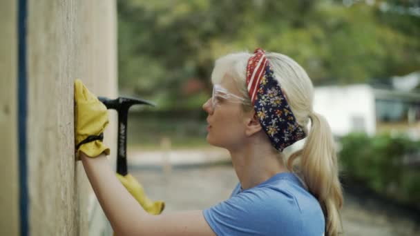 Female Construction Worker Hammers Nail Plywood Outdoors Medium — Stockvideo
