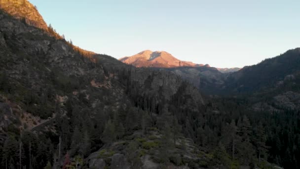 カリフォルニア州ソノラ パスを通る風の強い道路からの空中パンは 前景に木がある日没時に — ストック動画