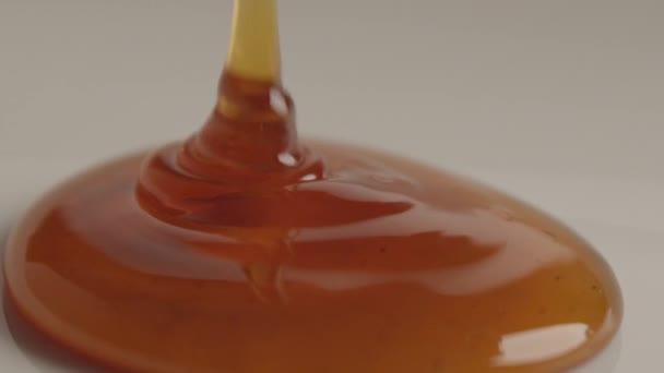 Макро Студийный Продукт Выстрел Натурального Оранжевого Меда Льется Белую Поверхность — стоковое видео