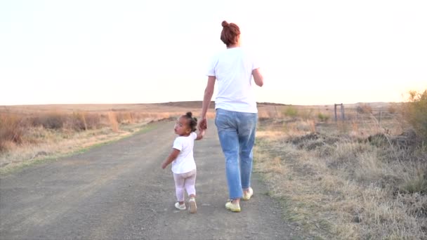 南非的母亲和女儿走在远离摄像头的土路上 而女儿则看着摄像头 跌跌撞撞 — 图库视频影像