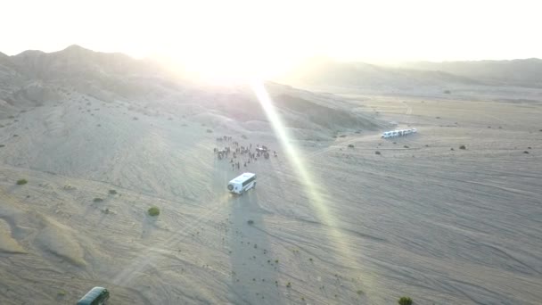ナミビア砂漠の人々のグループに向かって運転するバスのフライオーバー — ストック動画